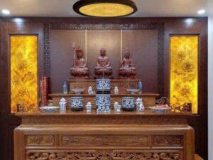 Hai bức tranh trúc chỉ hoa sen treo hai bên bàn thờ, chiếu sáng phía sau trong phòng thờ gỗ